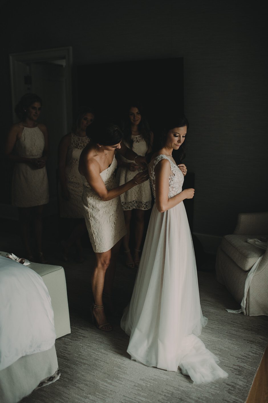 bridesmaids helping bride into dress