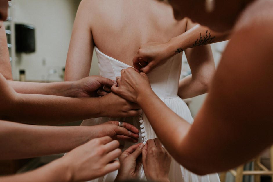 bridesmaids helping bride with dress, mostly just hands