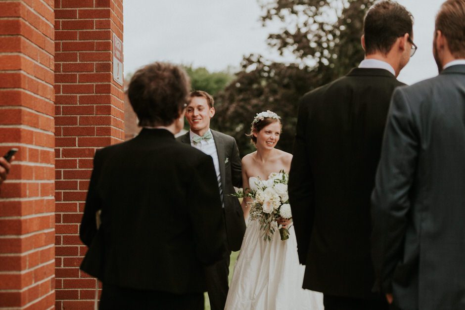 bride and groom greeting guests outside of church, laughing and smiling