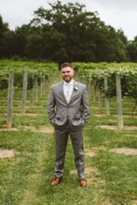 groom in a vineyard with a grey suit and floral tie