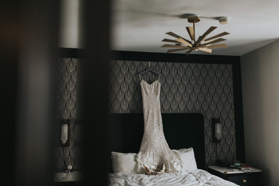 wedding dress hanging above hotel bed. a common image taken during wedding preparations 