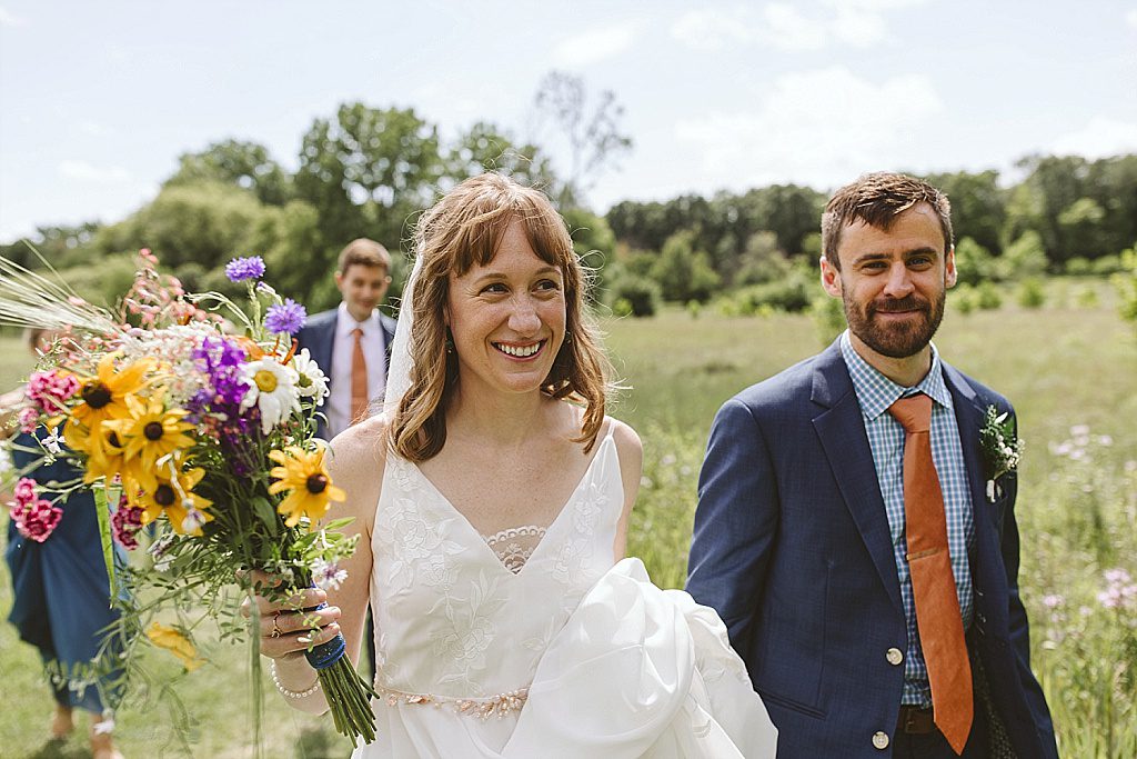 Bride and groom walking through the forest at Fenner Nature Center wedding