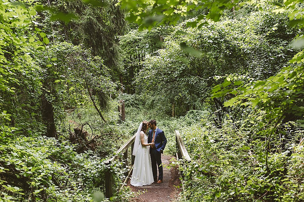 Bride and groom walking through the forest at Fenner Nature Center wedding