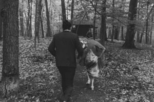 couple running through the woods in the rain at long lake outdoor center for a wedding